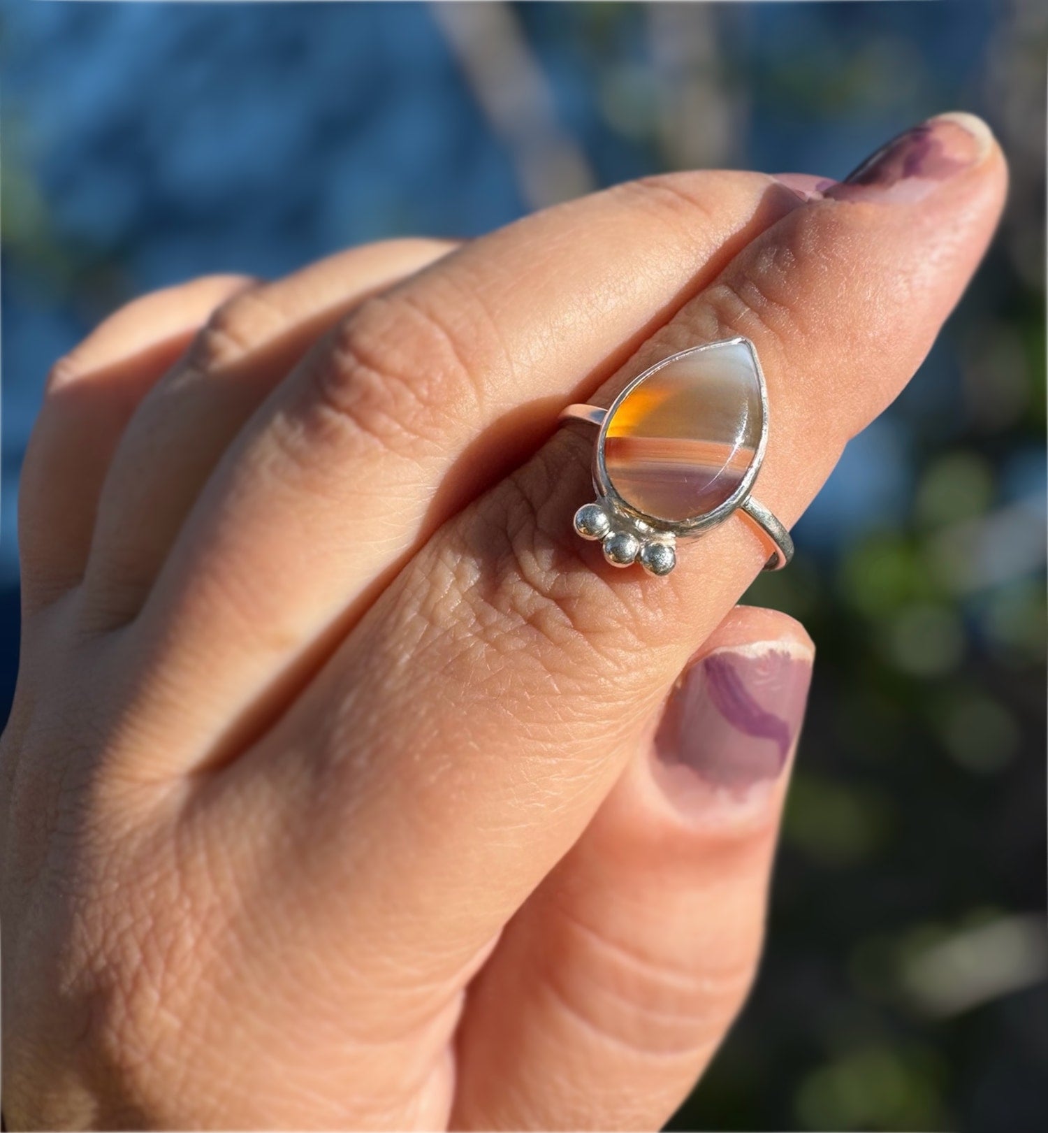 Hand wearing a handmade silver ring with botswana agate stone