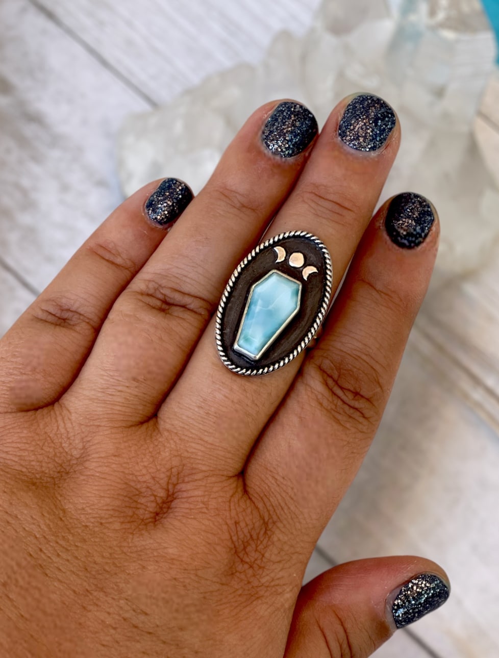 Larimar coffin stone moon phase silver ring shown on hand.