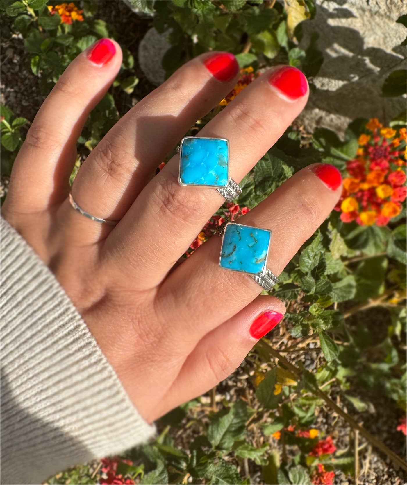 Two Kingman turquoise square sterling silver rings shown on hand.