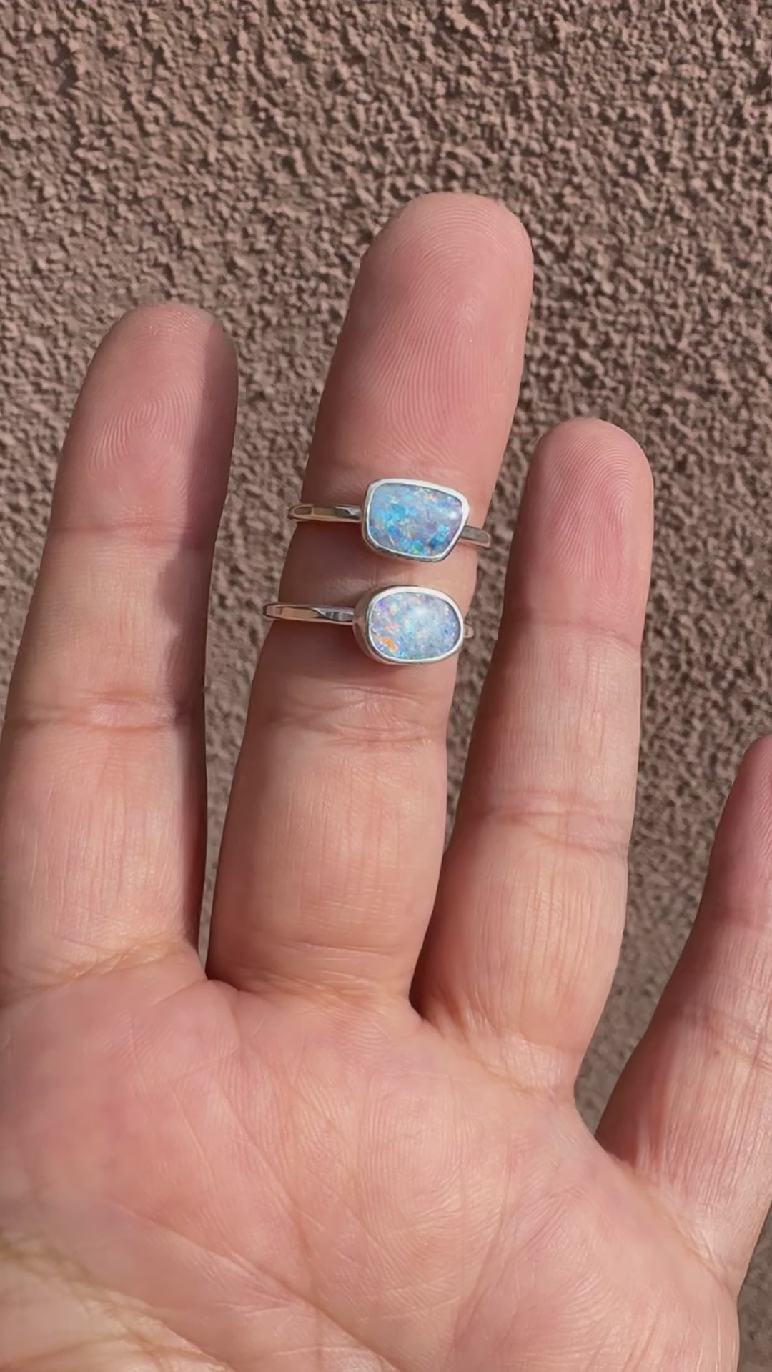 A video showing two handmade fiery Australian opal sterling silver solitaire rings worn on finger