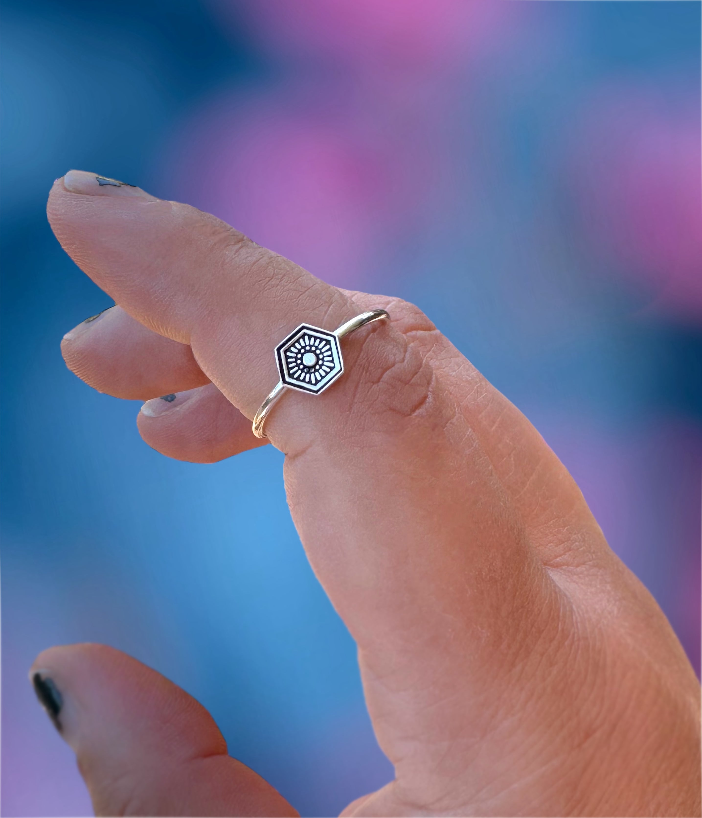 A handmade hexagon shaped stamped stacker ring shown on finger