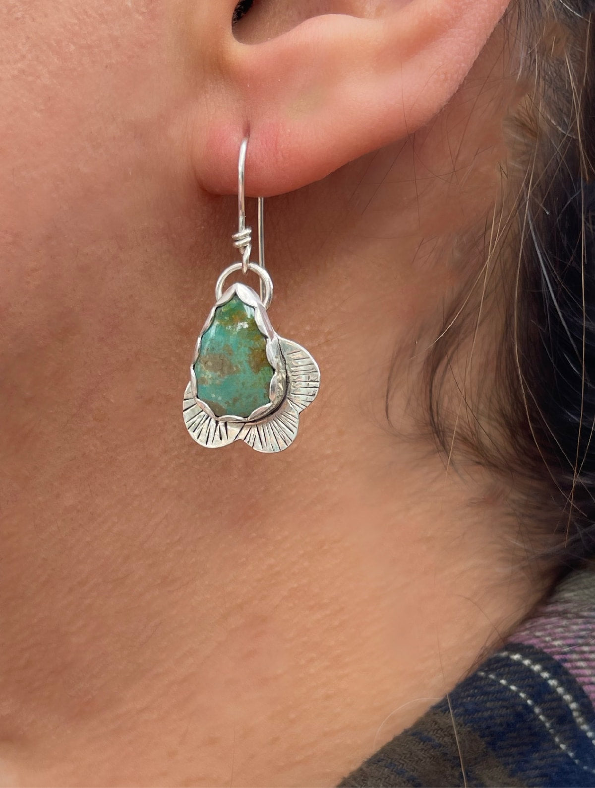 Kingman teardrop shaped turquoise stones with curvy silver line stamped edge shown worn in ears