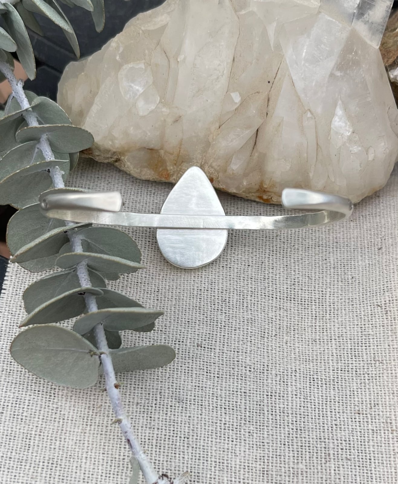 back view of sterling silver handstamped cuff bracelet with a big teardrop shaped jasper stone in a scalloped edge bezel