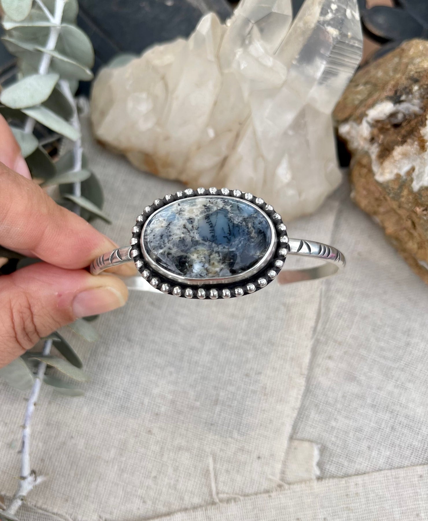 handstamped sterling silver cuff bracelet with a round dendritic opal stone with sterling bead wire around it